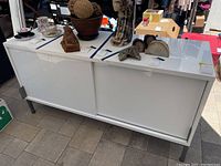 Front view of the white sideboard cabinet with two sliding doors, items placed on top but not included.
