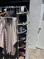 Photo showing hanging hat rack with six compartments containing several hats and a shoe stretcher hanging beside clothing rack