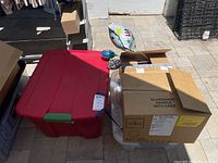 Large red plastic storage bin and cardboard box with bubble wrap, likely containing holiday decorations and paper goods.