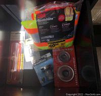 Photo of 3M Scotchlite safety vests in package, tub drain stopper, sink strainers, and small wooden handle tool.