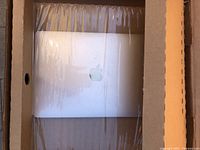 MacBook Air laptop inside a plastic wrap placed in a cardboard box, showing the Apple logo on the lid