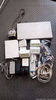Top-down photo showing all lot items including the silver Sony DVD player, white Nintendo Wii console, metal clock, power strips, cables, and adapters.
