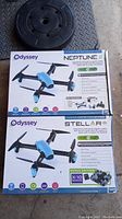 Boxes of Odyssey Neptune II and Stellar NX camera drones stacked with black weight plate