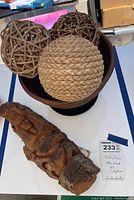 Photo showing the carved cottonwood bark sculpture beside a wooden vase containing three woven decorative balls.