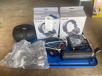 Photo showing two Tascam TH-03 headphones in box, Nura headphones, microphone case, and cables on floor.