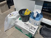 Wide view of Vicks humidifier, black bucket with toiletries, and box of bath tissue underneath.