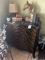 Full view of animal print wood cabinet topped with decorative items for scale and detail.