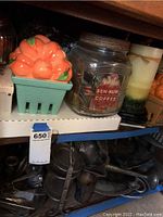 Full shelf view showing various assorted candles including a ceramic pumpkin basket candle, Ben-Hur Coffee jar candle, and other candles.