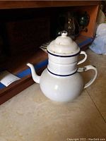 White enamel French coffee pot with blue stripes on countertop