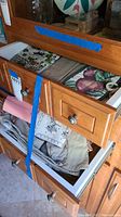 Two wooden drawers open showing multiple folded kitchen linens including printed and solid fabric pieces.