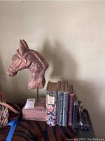 Photo showing carved wood horse sculpture, five vintage books, and Asian-style bookend.