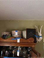 Photo of the lot showing three vintage stoneware crocks on a wooden cabinet top, small chalkboard, and white wall-mounted deer head with antlers.