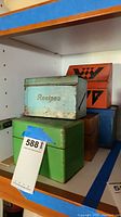 Shelf display of five vintage recipe boxes, including tin and wooden varieties with various colors and patterns.