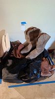 Wide view of six pairs of women's boots including tan suede cowboy boots, black tall boots, and various brown and rust-colored boots.