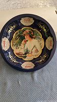 Top view of the 1995 Coca-Cola round serving tray showing central woman image and blue background with Coca-Cola logos on four white plaques