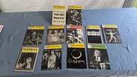Full view of all 10 vintage Playbill theatre programs arranged on blue cloth, showing various covers and titles.