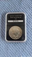 1924 Peace Silver Dollar coin encapsulated in plastic case with label stating 'Genuine Uncirculated Peace Silver Dollar 1924 90% Silver'.