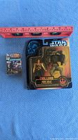 Two-piece lot showing Deluxe Han Solo figure with Battle Assault Scout Walker and Star Wars dice set with a ruler for scale on blue fabric background.