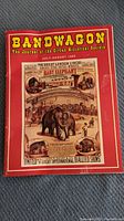 Photo of Bandwagon journal July-August 1995 edition with circus baby elephant poster on cover, red border