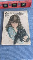 Front cover showing the entire magazine with illustration of girl holding black cat, vintage wear visible