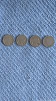 Four Buffalo nickel coins laid out in a row on blue carpet showing the obverse side with Native American profile.