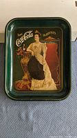 Metal serving tray with vintage Coca Cola advertisement featuring a woman in period dress, measuring approximately 13 inches tall.