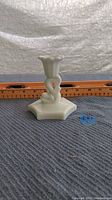 Full view of vintage white milk glass candlestick with dragon fish koi design, set against a ruler showing size measurement.