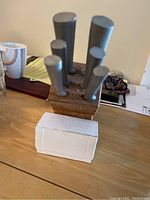 Full set of knives in a wooden knife block with metal handles and visible sharpening block attached.
