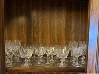 Full shelf view showing multiple crystal glasses grouped by type including liqueur, sherbet, large, medium and smaller glasses.