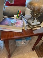 Top and side view of wooden side table with decorative edge and items placed on top for scale.