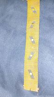 Full-length view of gold mesh cuff showing zig-zag pin window accents on grey surface
