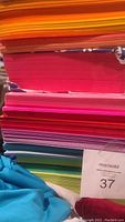 Stack of colorful letter-sized paper in shades including orange, pink, red, purple, blue, green.