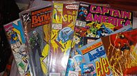 Front view of a collection of vintage comic books showing Captain America, The Amazing Spider-Man, The Many Deaths of Batman, and an Archie comic.