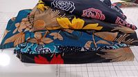 Stack of five folded blouses/shirts in various floral patterns and colors