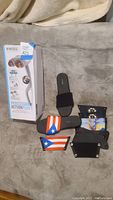 Photo showing HoMedics Percussion Action Plus massager box and ONESOLE shoe with five interchangeable Strappies tops in various designs including solid black, Puerto Rican flags, and colorful patterns.