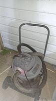 Full view of the Shop-Vac-Super canister vacuum with hose and metal frame with wheels and handlebar, showing size and structure.