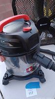 Porter-Cable stainless steel canister vacuum with red handle and black caster-wheel base, showing the logo and hose connection.