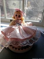 Frontal view of the vintage Madame Alexander Caroline doll wearing a pink and white lace dress with a pink bow in her blonde hair, showing face and upper body.