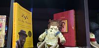 American Girl Addy doll seated with rag doll and two books behind on shelf