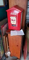 Red Randix fire emergency phone closed, showing front with 'FOR FIRE' text, pull-down hook instructions, and 911 label. Approximately 14 inches tall.