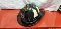 Side view of the black vintage Cairns Brother firefighter helmet with number 9 and MFD plate on front, beige panels visible.