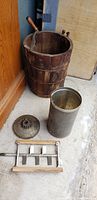 Antique wooden ice cream maker bucket with metal and wood hand crank, metal ice cream canister and lid, along with metal waffle and grill plates and a tin biscuit box.