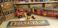 Overview of vintage firetruck toys, wooden Fireman sign, and fire extinguisher box on shelf.
