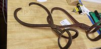 Photo of two large primitive iron ice tongs showing rust and looped handles.