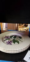 Set of three Royal Cauldron plates with floral design stacked, showing details of edge texture and flower pattern.