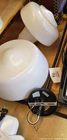 Photo of two white glass school house light globes and one metal light fixture mounting base showing condition and details.