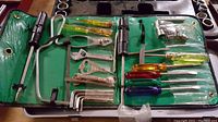 Vintage tool kit laid out flat showing assortment of hand tools in foldable green case