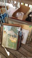 Nine framed and unframed art pieces stacked, showing one labeled Parsifal by Riccardo Wagner and others with varying frame styles and sizes