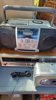 Photo showing Koss cassette boombox with CD player on top along with Realistic receiver below and small silver radio on right.