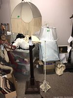 Full view of both floor lamps showing wooden base lamp with fringe shade and metal base lamp with white shade